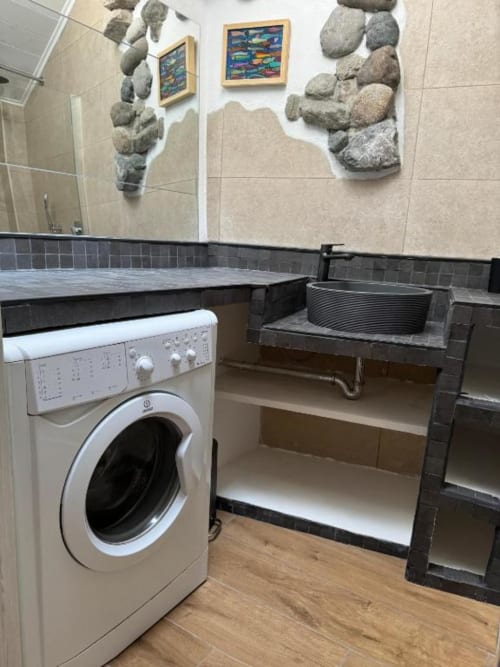 Moderno bagno lavanderia nell'appartamento Sormano con lavatrice, lavabo e decorativo rivestimento in pietra