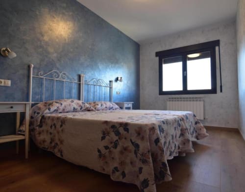 Dormitorio en la cabaña Tradición Rural de Nieva con pared de acento azul, cama de estructura metálica y vistas a la ciudad