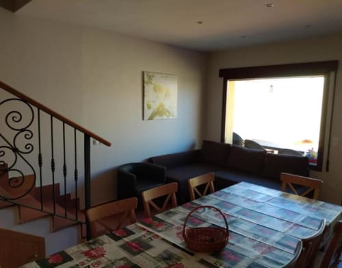 Sala de estar acogedora con mesa de comedor, sofá negro, escalera de madera con barandilla de hierro forjado y vistas a la ciudad en Tradición