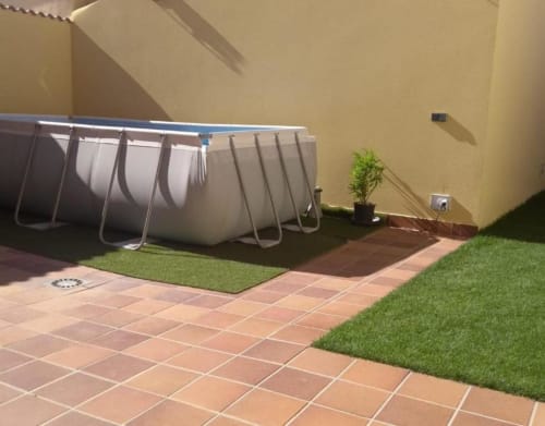 Patio de cabaña en Tradición Rural con piscina rectangular, césped sintético, baldosas de terracota y muro amarillo en Nieva