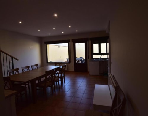 Amplio comedor de cabaña con mesa de madera, iluminación empotrada y grandes ventanales con vistas a Nieva