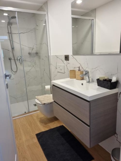 Bagno moderno a Maso Kreuzberg con piastrelle in marmo, doccia in vetro, mobiletto in legno e lavabo bianco
