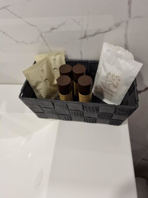 Cesto benvenuto del Maso Kreuzberg B&B Trento con prodotti spa, candele, caffè e articoli da bagno su fondo marmoreo