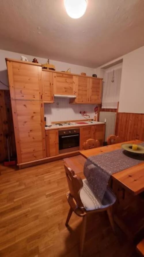 Cucina e zona pranzo in legno dell'appartamento Maso Kreuzberg a Trento con tavolo e vista sul giardino