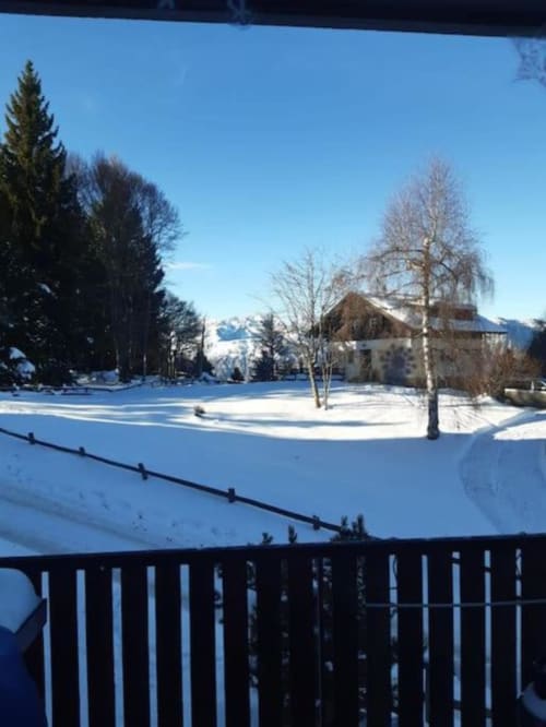 Vista invernale innevata del giardino di Maso Kreuzberg a Trento con montagne, alberi e edificio tradizionale