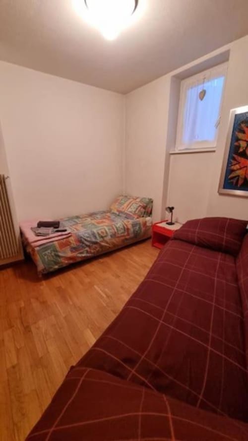 Accogliente camera da letto presso il BnB Maso Kreuzberg a Trento con due letti, pavimento in legno e vista sul giardino