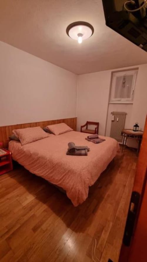 Camera accogliente presso il B&B Maso Kreuzberg a Trento con biancheria rosa, pavimenti in legno e lampada al soffitto