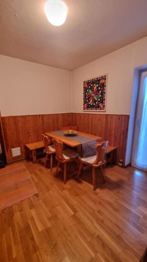 Zona pranzo del Maso Kreuzberg con tavolo in legno, sedie e coloratissimi dipinti alle pareti nell'appartamento di Trento