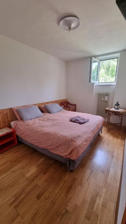 Camera luminosa al Maso Kreuzberg B&B di Trento con pavimenti in legno, biancheria rosa e vista sul giardino