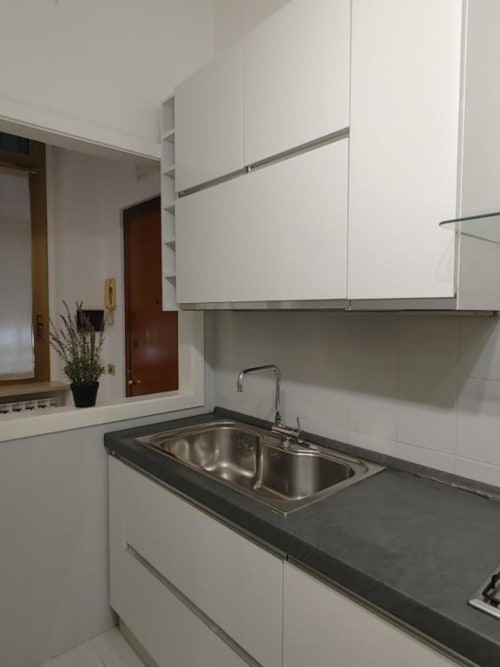 Moderna cucina nell'Apartment Mazzini di THE V Collection a Turate, con lavello in acciaio inox, piano di lavoro scuro e bianco