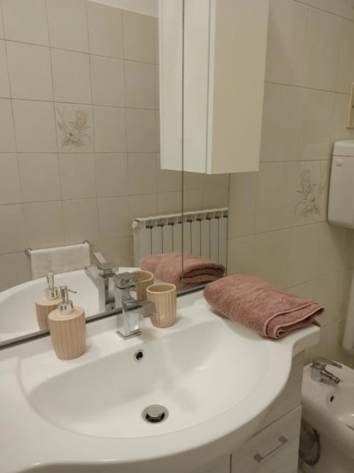 Bagno moderno con accessori in legno e asciugamani rosa piegati presso l'Apartment Mazzini, THE V Collection, Turate