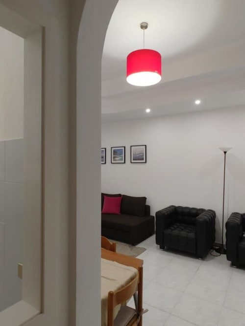 Moderno soggiorno con lampada a sospensione rossa, divani neri e opere d'arte incorniciate all'Apartment Mazzini di Turate, Italia