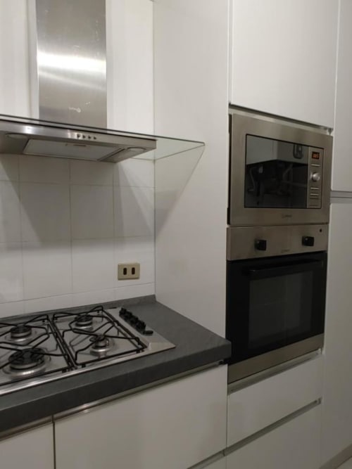 Cucina moderna nell'Apartment Mazzini di THE V Collection, Turate con piano cottura a gas in acciaio inox, forno a parete e finiture bianche
