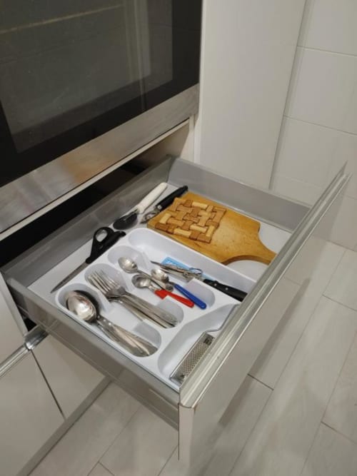 Cassetto cucina aperto nell'Apartment Mazzini di THE V Collection con utensili organizzati, posate e tagliere in legno