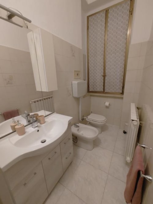 Moderno bagno con lavabo bianco, bidet, WC e finestra nell'Appartamento Mazzini di THE V Collection, Turate