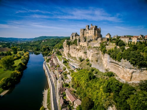 Le château de Neuschwanstein perché sur une falaise rocheuse dominant une vallée verdoyante et un ciel azuré