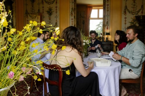 Des invités dînent ensemble au Château de Vaux Morvan à Étang sur Arroux avec des fleurs jaunes sur la table