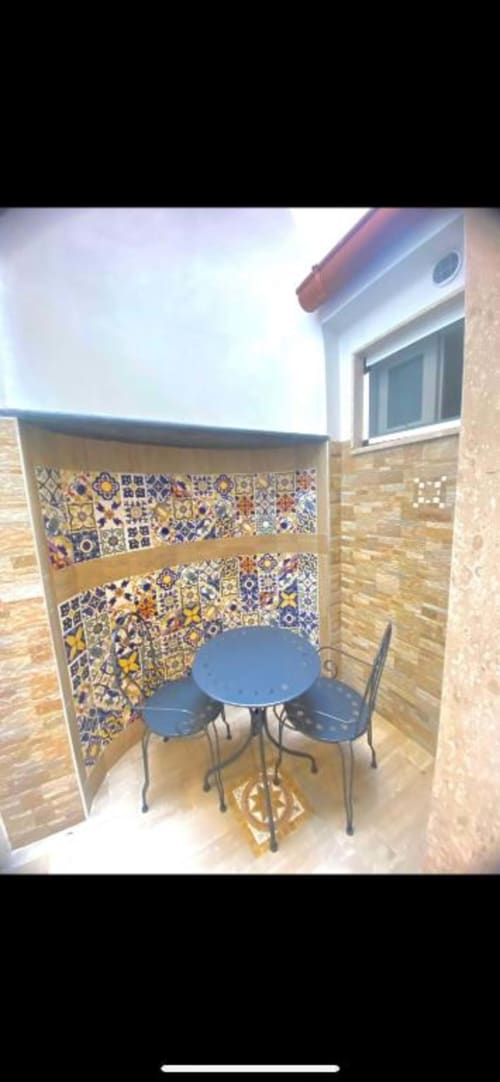 Accogliente angolo pranzo all'aperto presso San Nicola Suite Mini Apartments a Sorrento con piastrelle marocchine colorate e tavolo blu