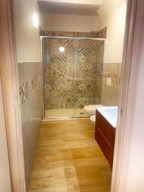 Bagno moderno in San Nicola Suite Mini Apartments a Sorrento con doccia in piastrelle decorate, pavimento in legno e lavabo