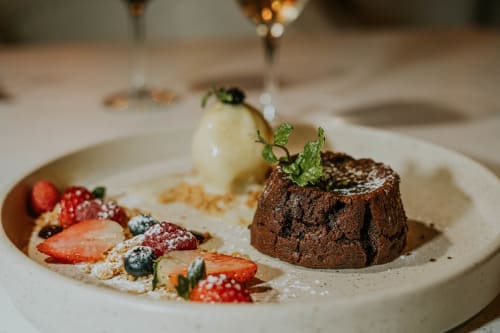 Elegante presentación de postre en Hotel 40 Cañones Mahahual: torta de chocolate, helado de vainilla, frutos rojos frescos y menta