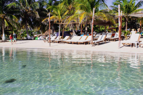 Playa tropical con agua turquesa cristalina, palmeras y tumbonas en el Hotel 40 Cañones de Mahahual