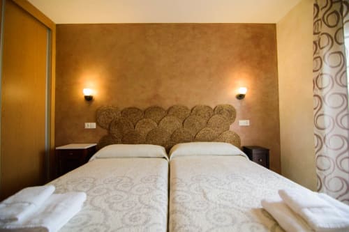 Acogedora habitación con camas gemelas, cabecero tejido e iluminación ambiente en la Tradición Rural de Nieva