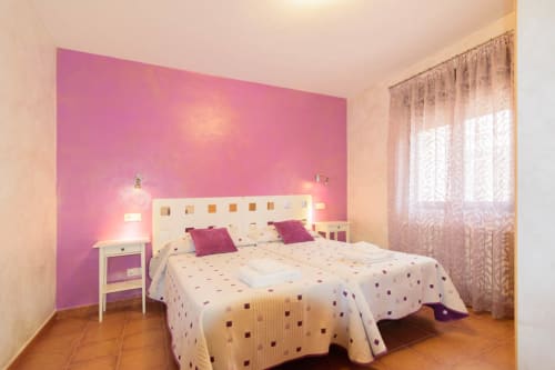 Habitación luminosa en la cabaña Tradición Rural de Nieva con pared de acento rosa, cama doble y vista al jardín