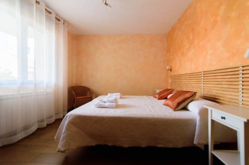 Luminoso dormitorio de la cabaña en Tradición Rural de Nieva con paredes texturadas naranjas, cabecero de madera y vistas al jardín