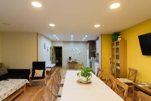 Interior de cabaña amarillo brillante en Tradición Rural con mesa de comedor, sillas de madera y vista al jardín