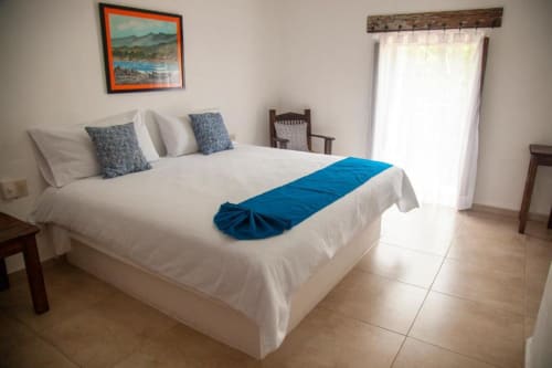 Bright hotel room at La Familia Hotel in San Blas with white bed, blue accents, and natural light from balcony doors