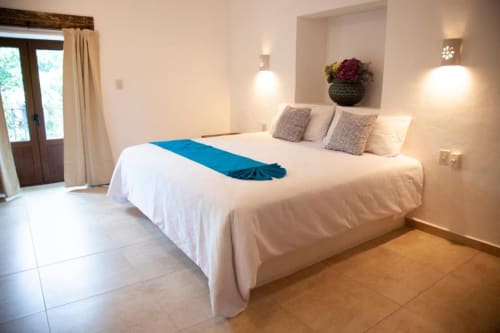 Spacious hotel bedroom at La Familia Hotel y Restaurante in San Blas, Nayarit with white bed, blue accent, and city view