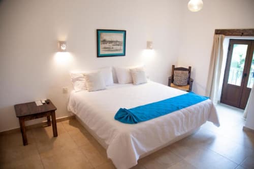Bright hotel room at La Familia Hotel in San Blas, Nayarit with white bedding, blue bed runner, and modern lighting fixtures