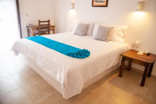 Bright hotel room at La Familia Hotel with king bed, blue runner, wooden desk, and city view in San Blas, Nayarit