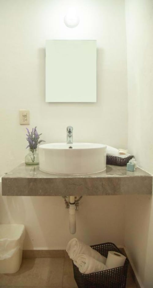 Minimalist bathroom vanity at La Familia Hotel in San Blas with round white sink, lavender flowers, and neutral décor