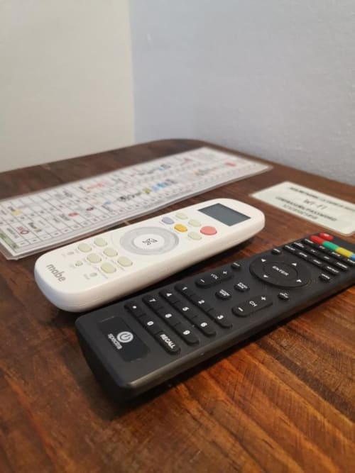 White and black remote controls with spreadsheet on wooden desk at La Familia Hotel, San Blas