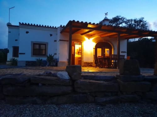 Villa Quim's House ao entardecer com luzes aconchegantes no terraço, arquitetura de paredes brancas, pérgola de madeira e jardim em Almodôvar