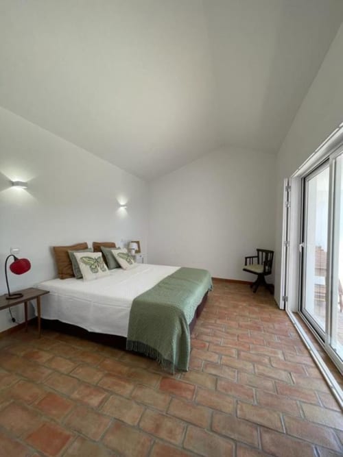 Quarto espaçoso na villa Vineyard House em Corvatos Casas do Monte com piso em terracota, cama de madeira, roupa de cama verde e
