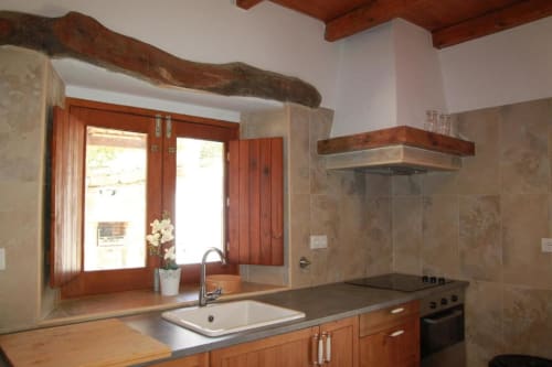 Modern kitchen with wooden beams and cabinetry, stainless steel appliances, and stone backsplash in Quim's House villa at