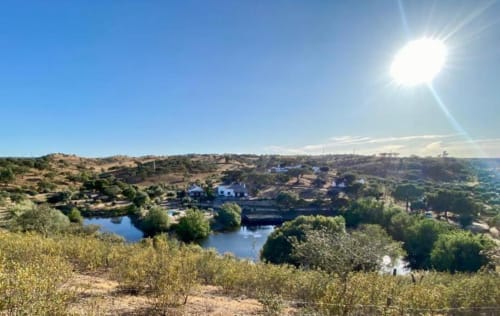 Scenic lake view of Corvatos Casas do Monte villa in Almodôvar, Portugal with surrounding hills and countryside under bright