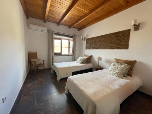 Twin bedroom with wooden ceiling beams at Corvatos Casas do Monte villa in Almodôvar, Portugal