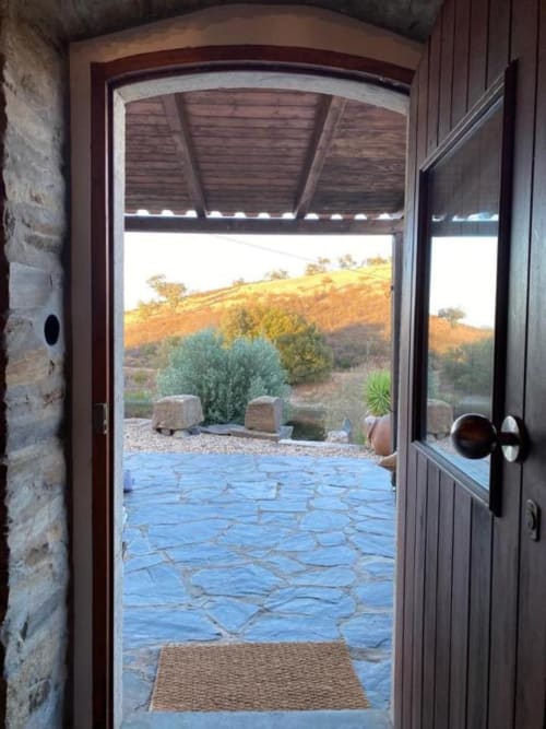 Open wooden door with mountain views at Corvatos Casas do Monte villa in Almodôvar, Portugal, showing blue stone patio and