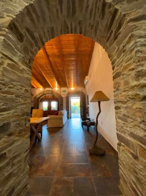 Stone archway entrance to Quim's House villa at Corvatos Casas do Monte in Almodôvar, Portugal, with wooden ceiling and