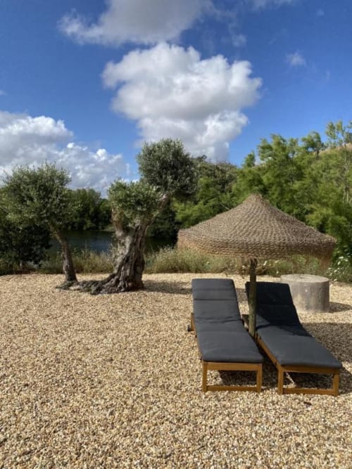Two lounge chairs on gravel patio overlooking lake at Corvatos Casas do Monte villa in Almodôvar, Portugal