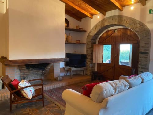 Spacious living room at Quim's House villa in Almodôvar with fireplace, sofa, TV, arched doorway, and exposed wooden beams