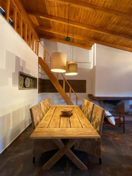 Modern dining area in Quim's House villa at Corvatos Casas do Monte with wooden table, pendant lights, and staircase.