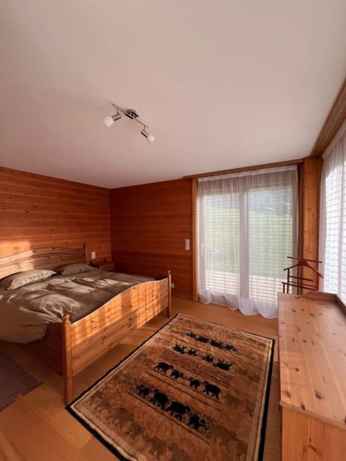 Chambre en bois à Grangette Villars avec lit double, portes donnant sur la montagne et décor alpin traditionnel