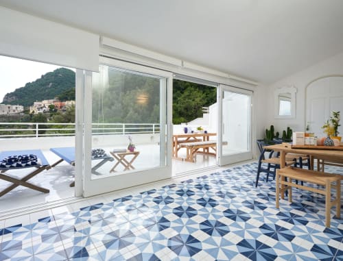 Luminosa camera moderna a Wonderful Positano con pavimento di piastrelle blu geometriche, mobili in legno e terrazza con vista su Positano