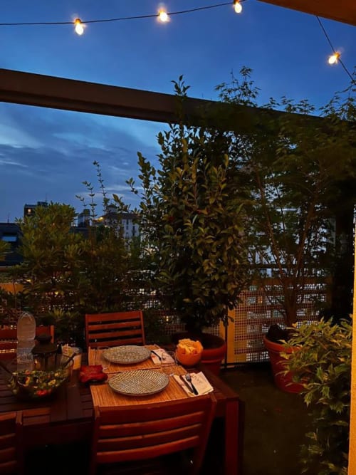 Terrazza con vista su Milano al tramonto di GIRESIO 41, con sedie rosse, tavoli apparecchiati, luci decorative