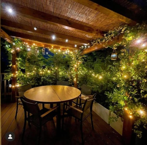 Terrazza sul tetto illuminata di GIRESIO 41 Milano con tavolo rotondo, pergolato in legno e verdure lussureggianti