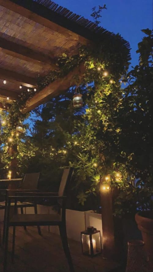 Terrazza serale elegante del GIRESIO 41 Milano BnB con edera illuminata, pergolato in legno e illuminazione d'atmosfera
